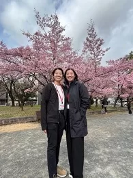 Kakehashi 2023 author and her twin posing in front of cherry blossom trees